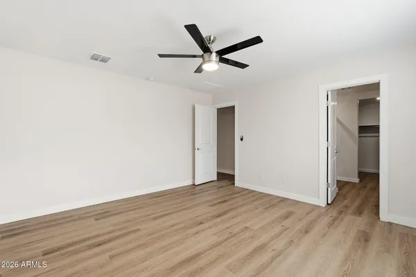 a view of a big room with wooden floor and a ceiling fan