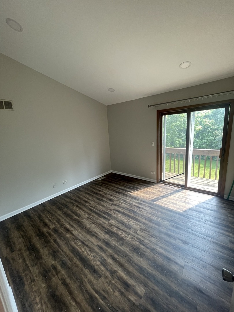 498 Nicole Drive, Unit A Bartlett, IL 60103 - Photo 6 of 7 a view of an empty room with wooden floor and a window