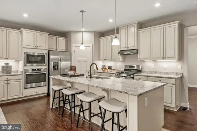 a kitchen with kitchen island granite countertop a table chairs sink and cabinets