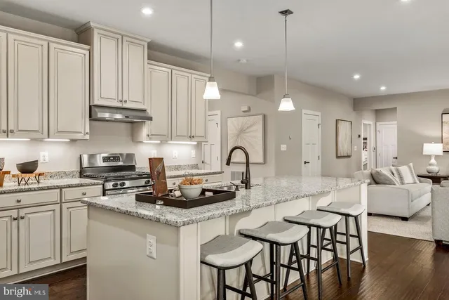 a kitchen with stainless steel appliances granite countertop a stove a sink dishwasher and white cabinets with wooden floor