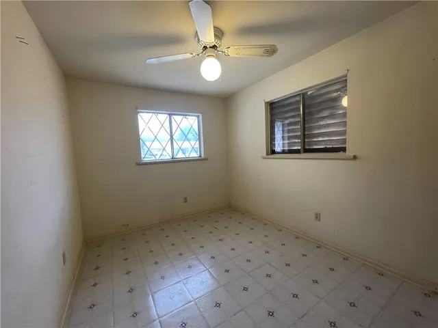 an empty room with windows and fan