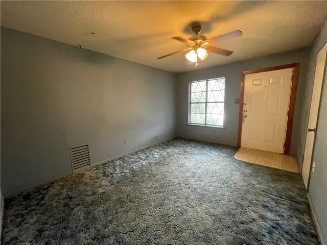 en empty room with windows and ceiling fan
