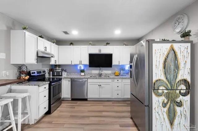 a kitchen with stainless steel appliances a stove top oven a refrigerator a sink and dishwasher