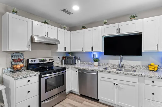 a kitchen with granite countertop a sink stainless steel appliances and white cabinets