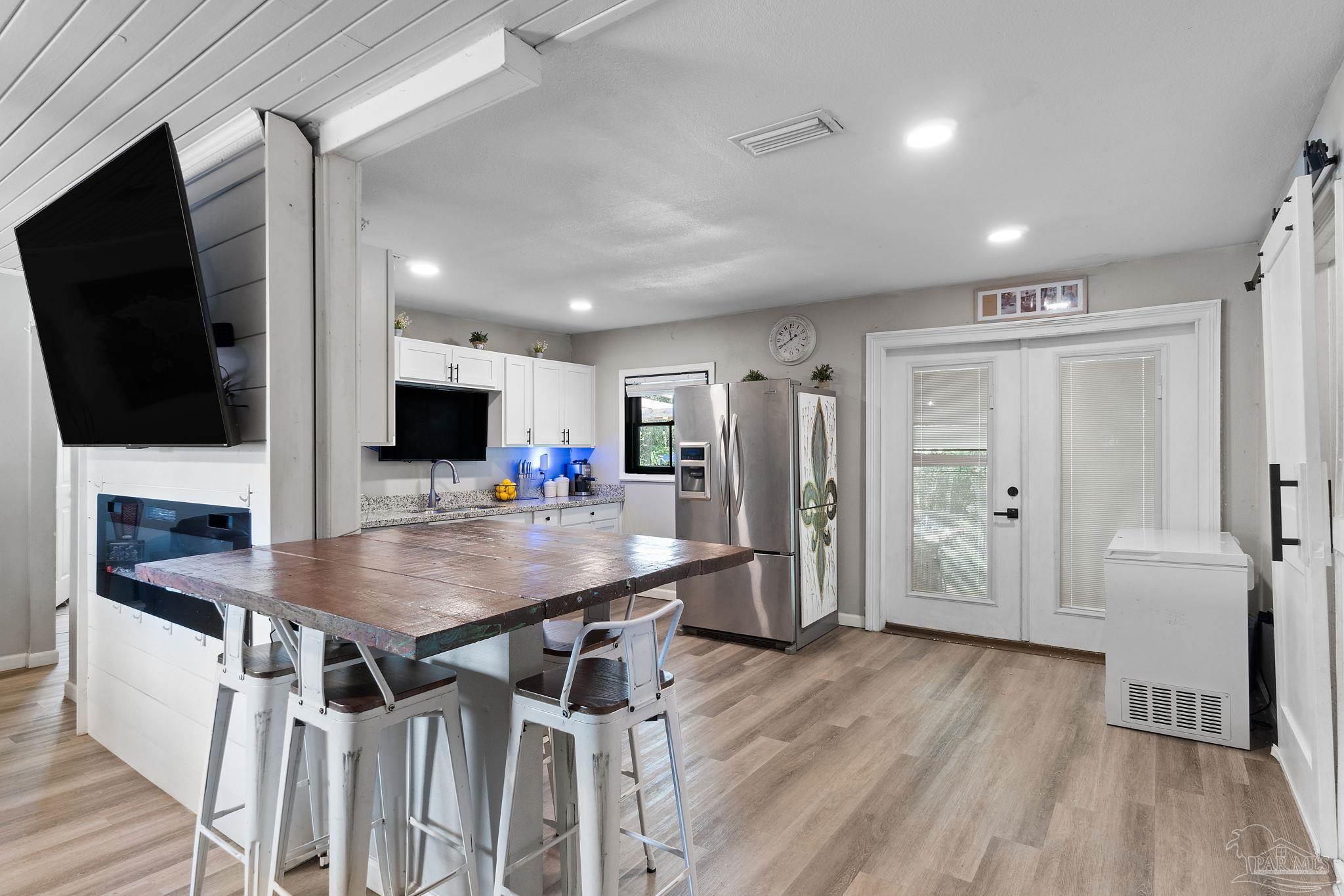10610 Chemstrand Road Pensacola, FL 32514 - Photo 10 of 42 a kitchen with stainless steel appliances kitchen island granite countertop a refrigerator a stove and a dining table with wooden floor