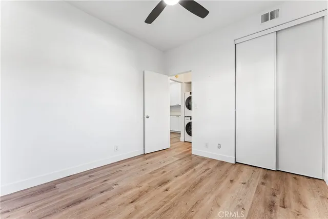 an empty room with wooden floor closet and windows
