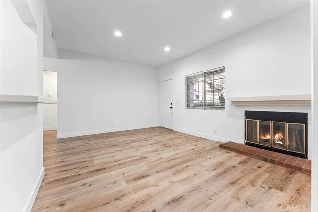 a view of empty room with wooden floor and fireplace