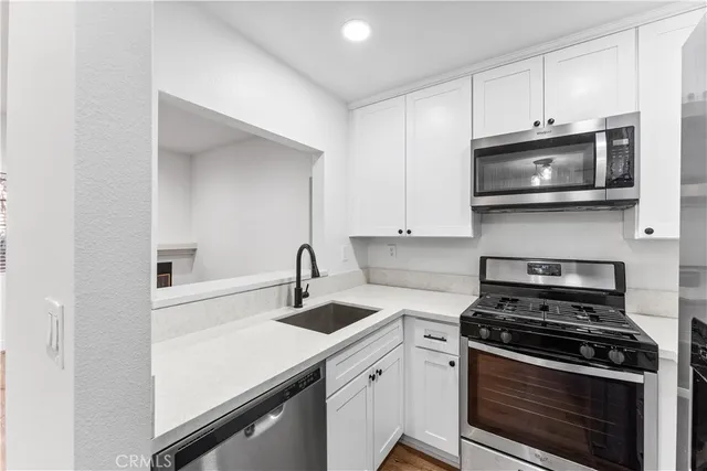 a kitchen with stainless steel appliances a stove a microwave a sink and cabinets