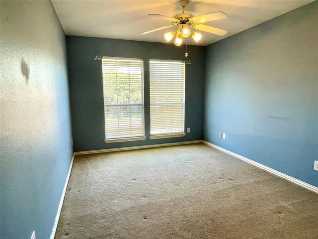 an empty room with a window and a ceiling fan