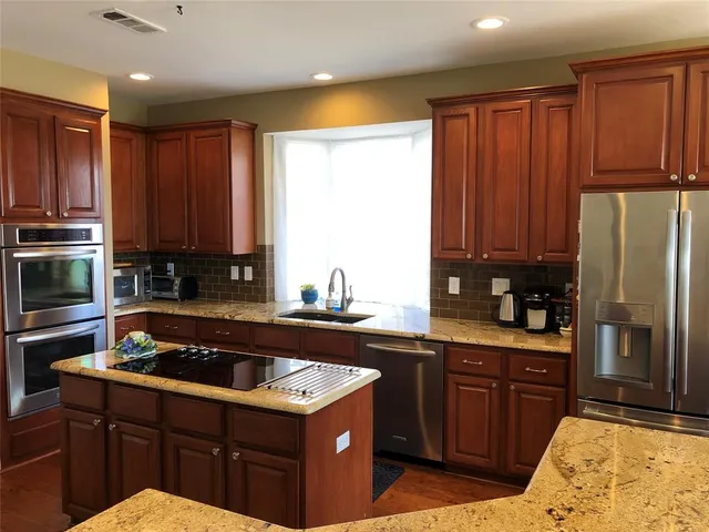 a kitchen with kitchen island granite countertop a sink stainless steel appliances and cabinets