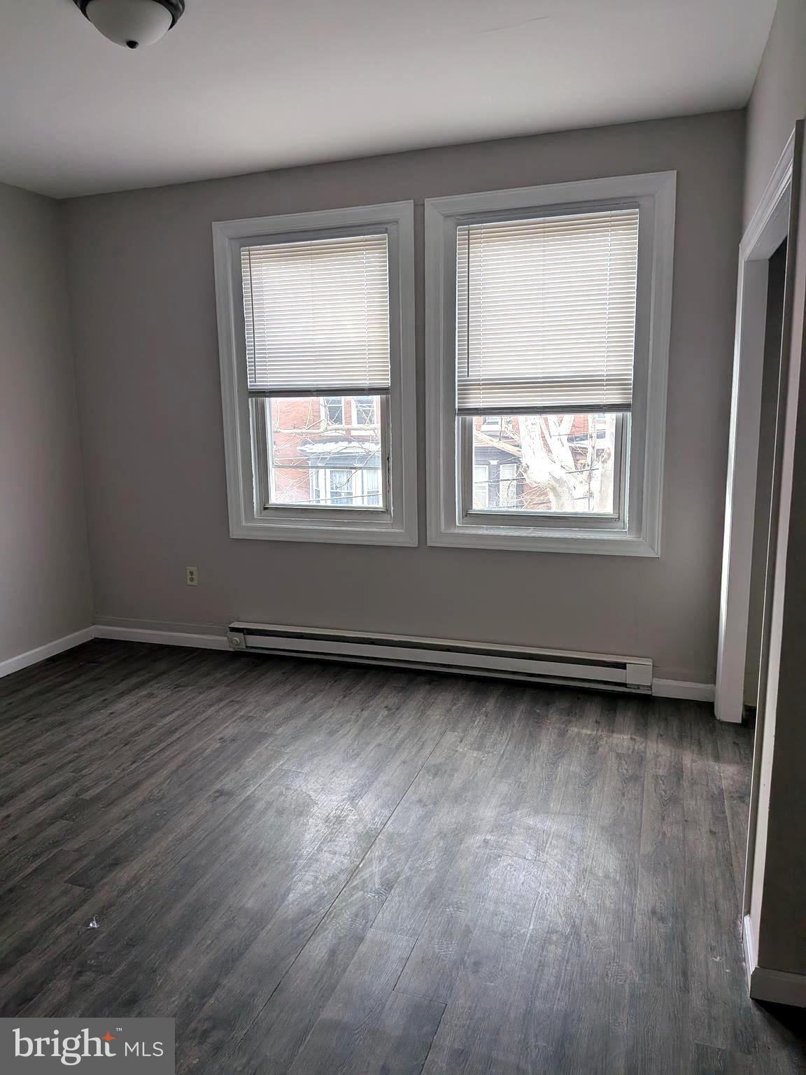 1343 West Pike Street, Unit 3 Philadelphia, PA 19140 - Photo 3 of 10 an empty room with wooden floor and windows