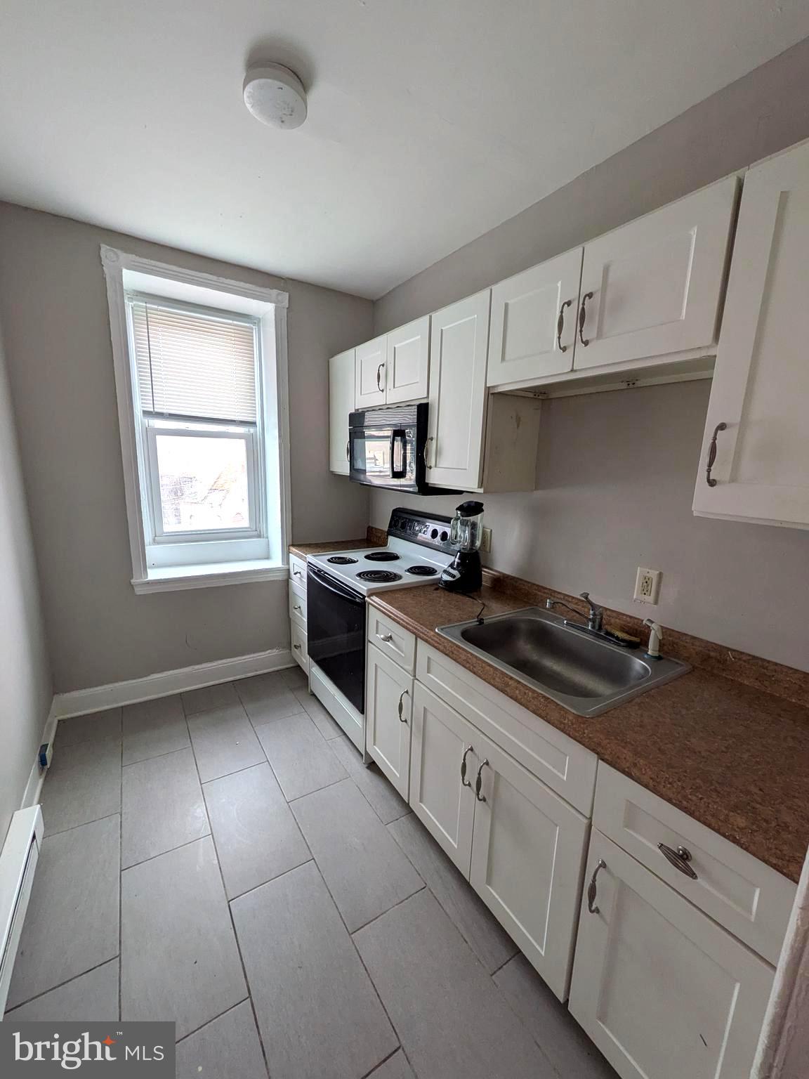 1343 West Pike Street, Unit 3 Philadelphia, PA 19140 - Photo 10 of 10 a kitchen with granite countertop white cabinets stainless steel appliances and a window