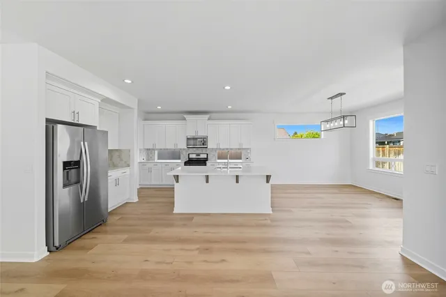 a view of kitchen with stainless steel appliances refrigerator stove microwave and cabinets