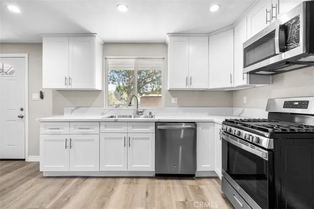 a kitchen with stainless steel appliances granite countertop a stove a sink and a microwave