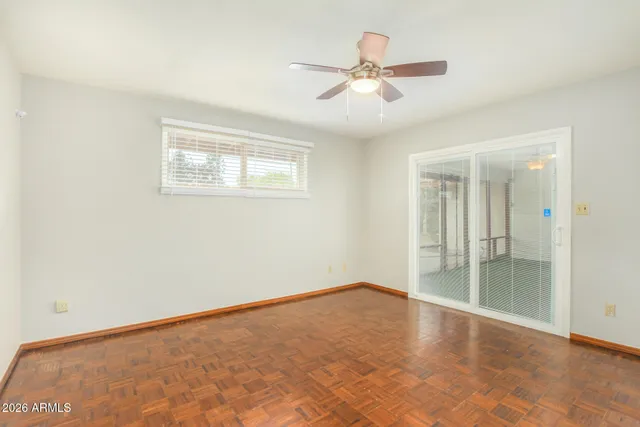 an empty room with wooden floor fan and windows