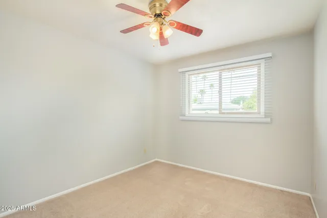 an empty room with a window and a fan