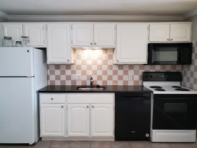 a kitchen with white cabinets and sink