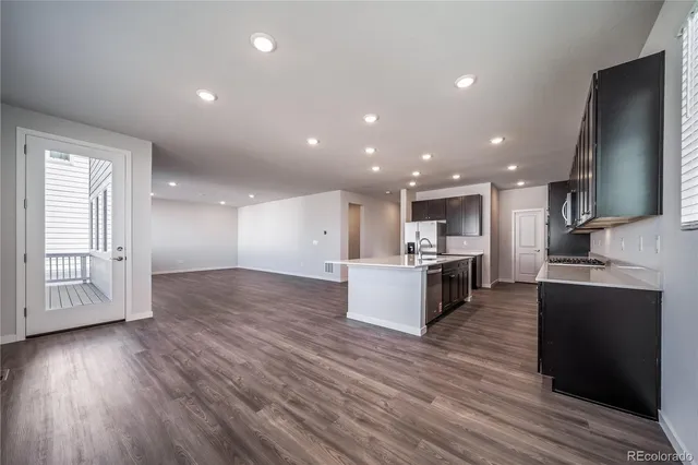 a large kitchen with stainless steel appliances kitchen island wooden floors and white cabinets