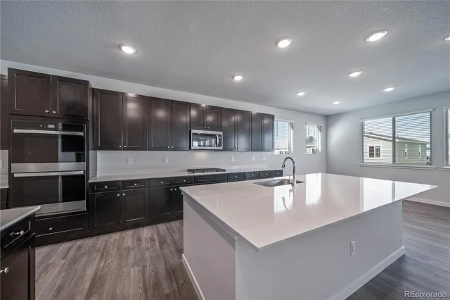 a large kitchen with stainless steel appliances a large counter top and oven