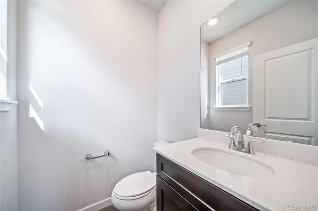a bathroom with a granite countertop sink a toilet and a mirror