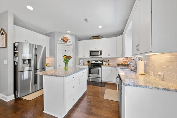 a kitchen with granite countertop a refrigerator a stove top oven a sink and dishwasher