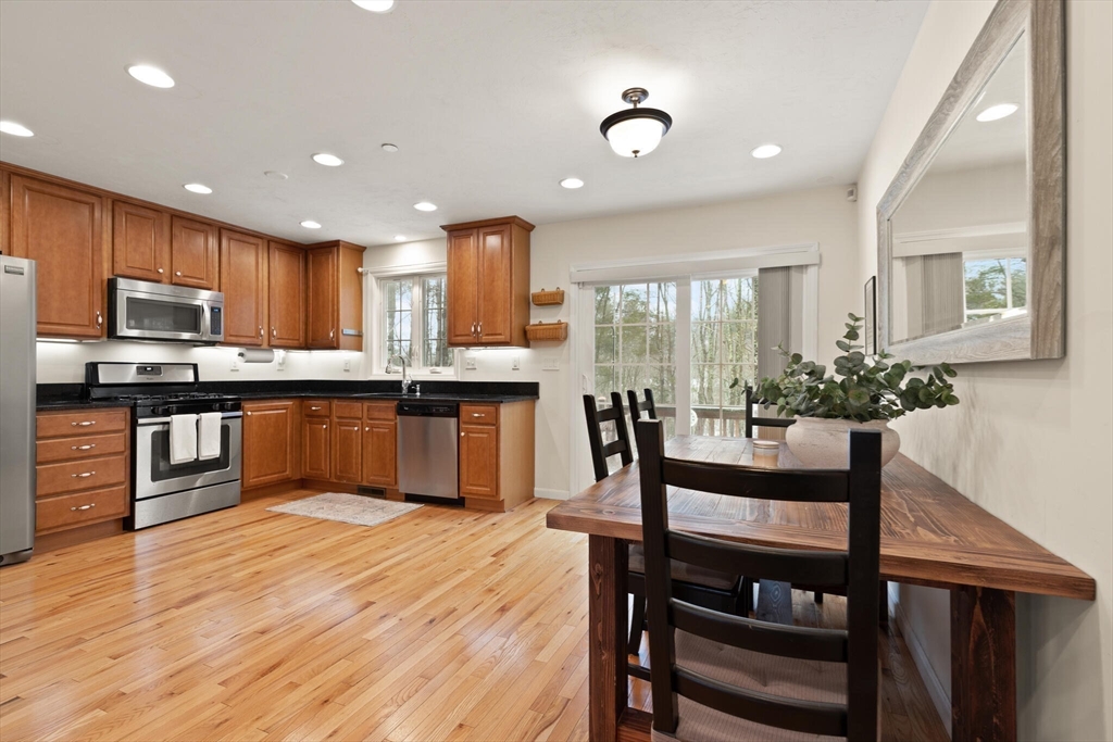 41 Boston Road, Unit 485 Billerica, MA 01862 - Photo 2 of 19 a kitchen with stainless steel appliances granite countertop a stove top oven a sink dishwasher a dining table and chairs with wooden floor
