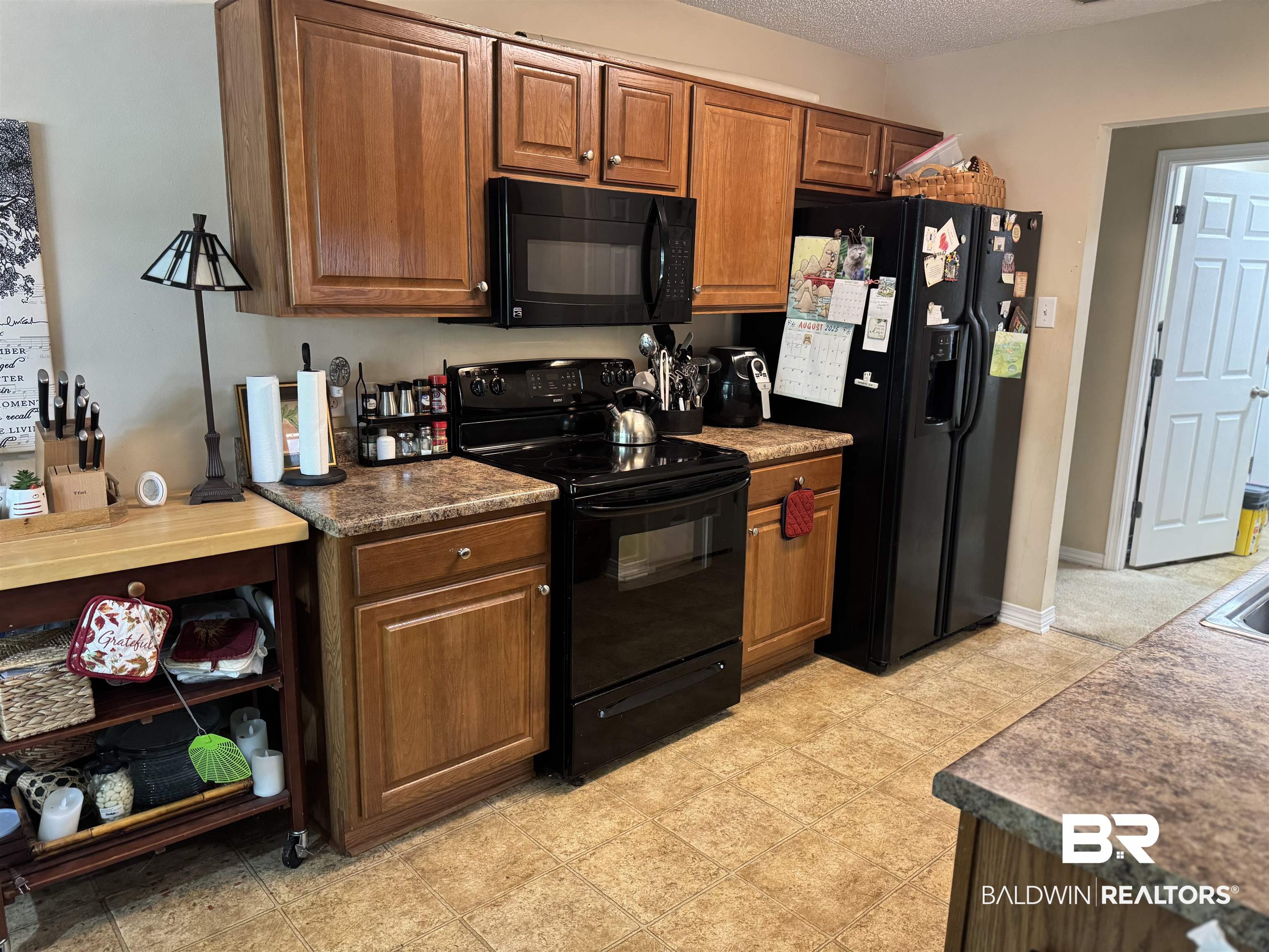 2245 Spring Grove North Mobile, AL 36695 - Photo 3 of 10 Kitchen featuring black appliances, dark countertops, brown cabinets, and a textured ceiling