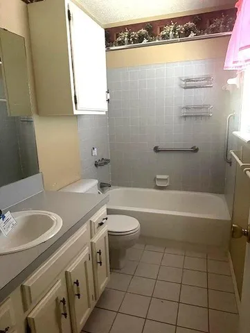 a bathroom with a granite countertop sink a toilet and bathtub