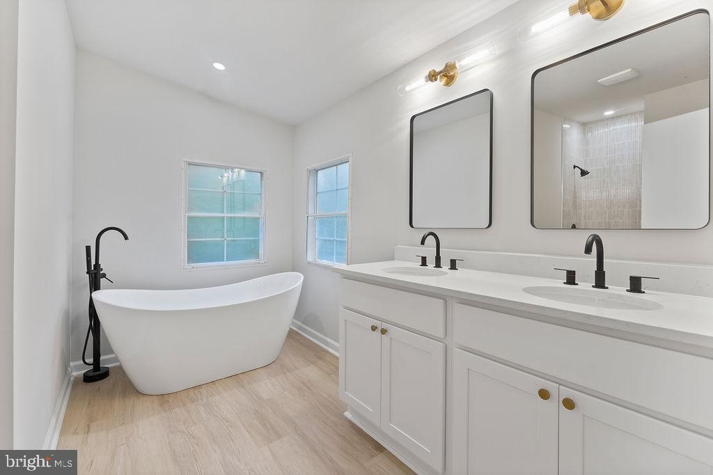1109 Eastham Road Bumpass, VA 23024 - Photo 15 of 26 a bathroom with a double vanity sink a mirror and a bathtub