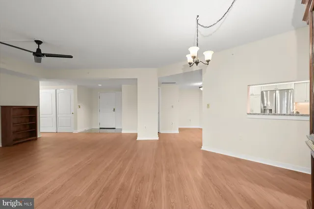 a view of empty room with wooden floor and fan