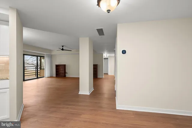 a view of empty room with wooden floor and fan