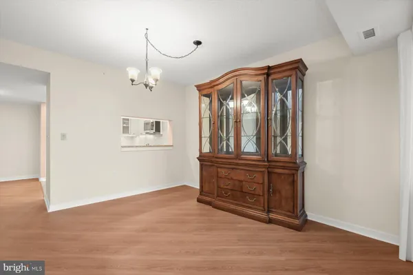 a view of a hallway with wooden floor and cabinet