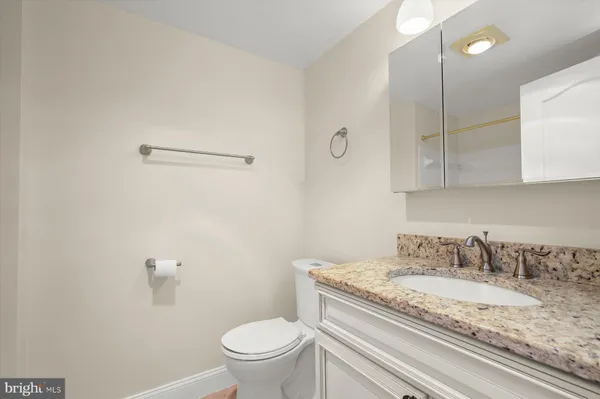 a bathroom with a granite countertop toilet sink and mirror