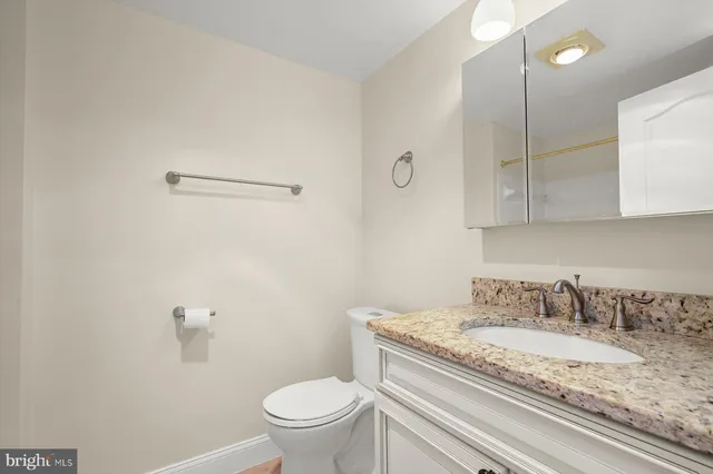 a bathroom with a granite countertop toilet sink and mirror