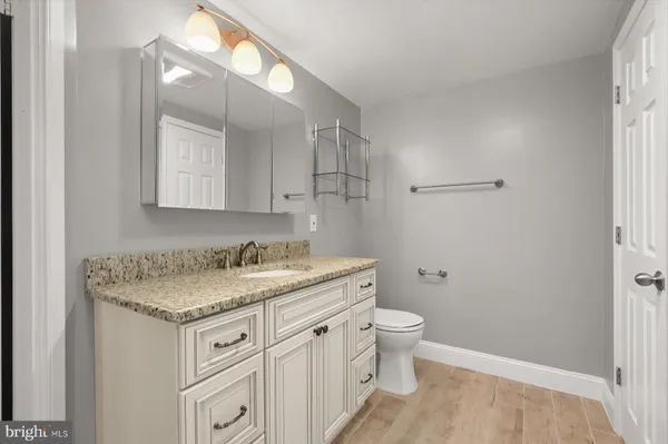 a bathroom with a granite countertop sink a toilet and a mirror