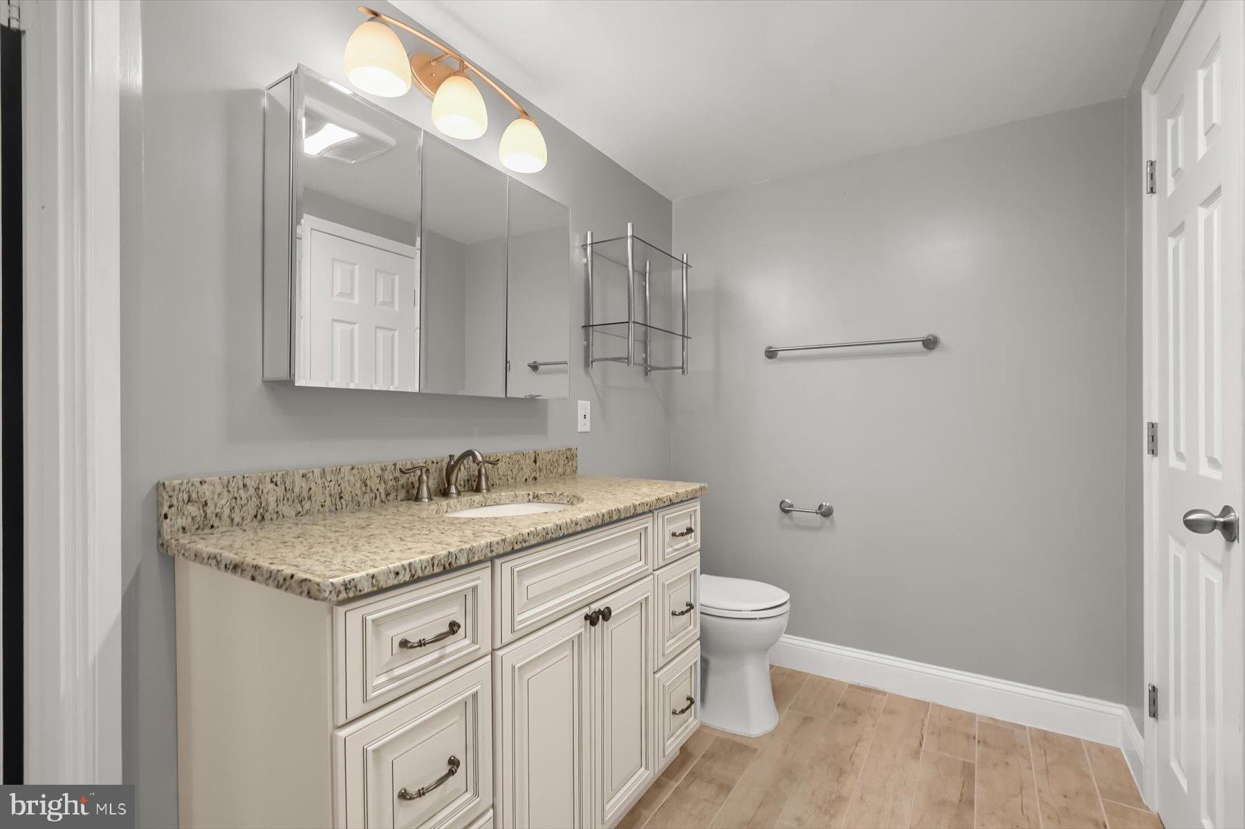 10001 Windstream Drive, Unit 404 Columbia, MD 21044 - Photo 33 of 51 a bathroom with a granite countertop sink a toilet and a mirror