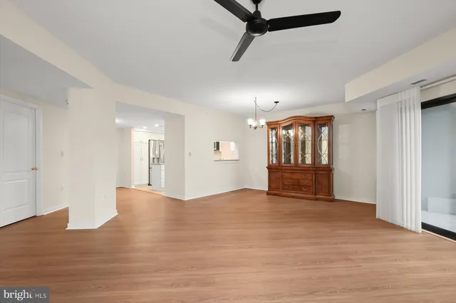 a view of an empty room with a window and wooden floor