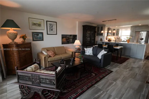 a living room with furniture a rug and kitchen view