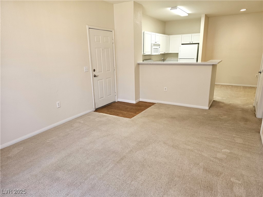 9000 South Las Vegas Boulevard, Unit 1176 Las Vegas, NV 89123 - Photo 11 of 26 Kitchen with light carpet, a peninsula, white cabinets, white appliances, and light countertops