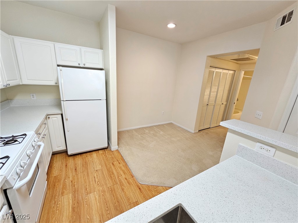 9000 South Las Vegas Boulevard, Unit 1176 Las Vegas, NV 89123 - Photo 5 of 26 Kitchen featuring white appliances, white cabinets, recessed lighting, light wood-type flooring, and light stone counters