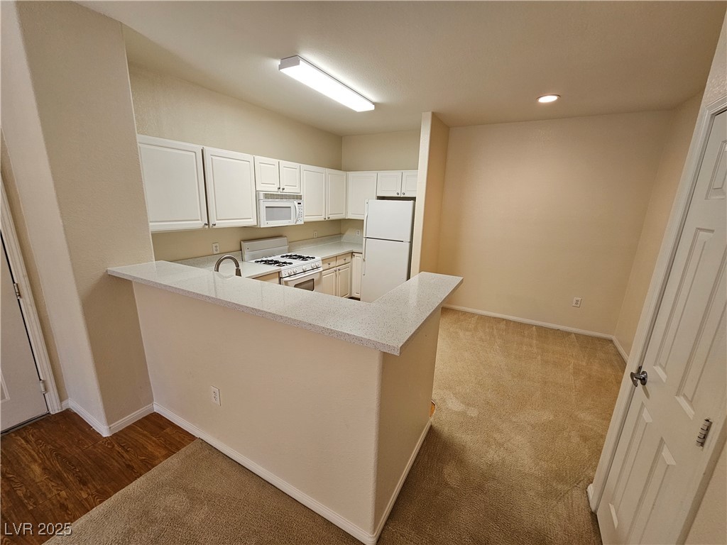 9000 South Las Vegas Boulevard, Unit 1176 Las Vegas, NV 89123 - Photo 6 of 26 Kitchen featuring white appliances, a peninsula, recessed lighting, light colored carpet, and white cabinetry