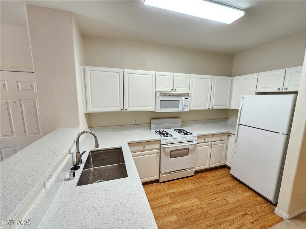 9000 South Las Vegas Boulevard, Unit 1176 Las Vegas, NV 89123 - Photo 8 of 26 Kitchen with white appliances, light wood-type flooring, white cabinetry, and light stone countertops