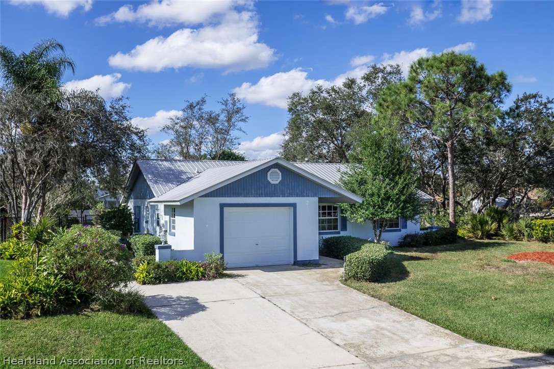 4115 Loquat Road Sebring, FL 33875 - Photo 27 of 28 a front view of a house with a garden and trees