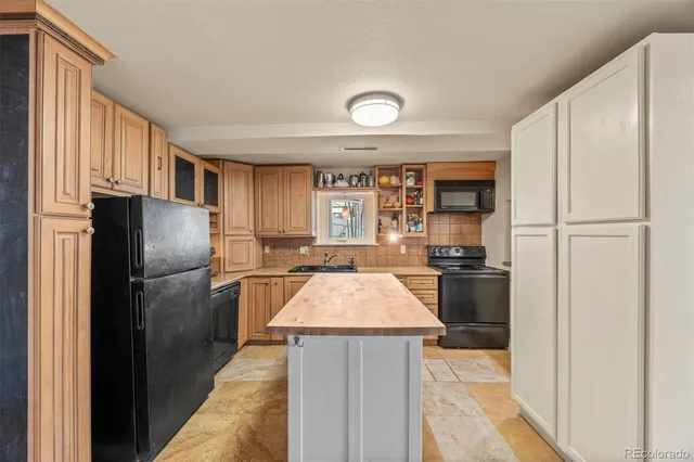 a kitchen that has a sink a stove and wooden cabinets