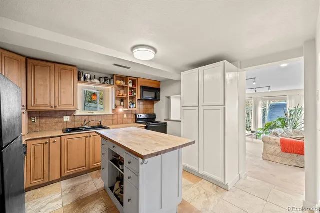 a kitchen with stainless steel appliances kitchen island granite countertop a table chairs and a refrigerator