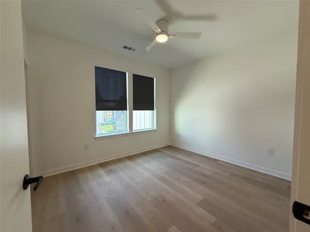 an empty room with wooden floor cabinet and windows