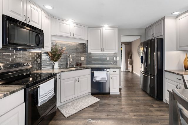 a kitchen with kitchen island granite countertop stainless steel appliances and wooden cabinets
