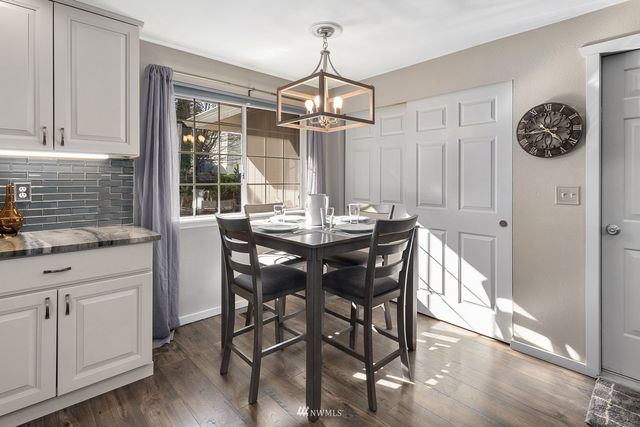 a dining room with wooden floor a chandelier a wooden table and chairs