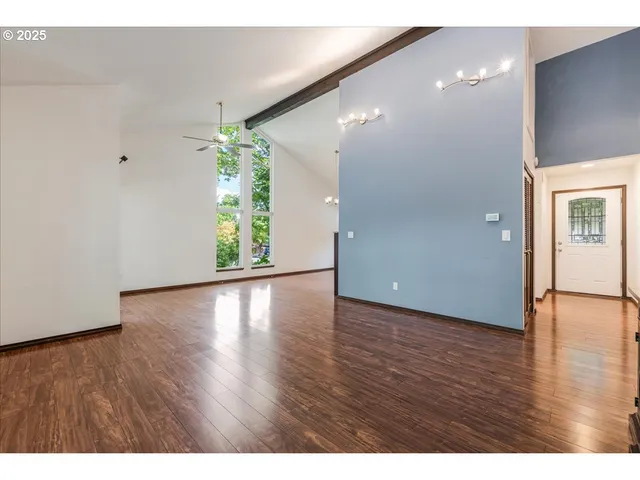 a view of an empty room with window and wooden floor