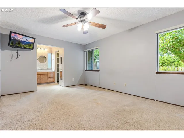 an empty room with windows and chandelier fan